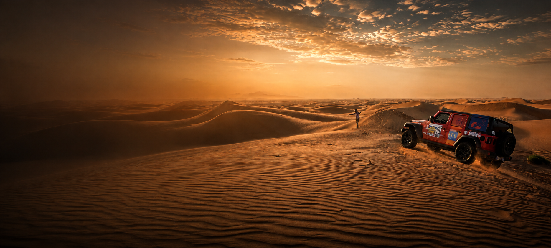 Véhicule de rallye dans les dunes du désert marocain au coucher du soleil